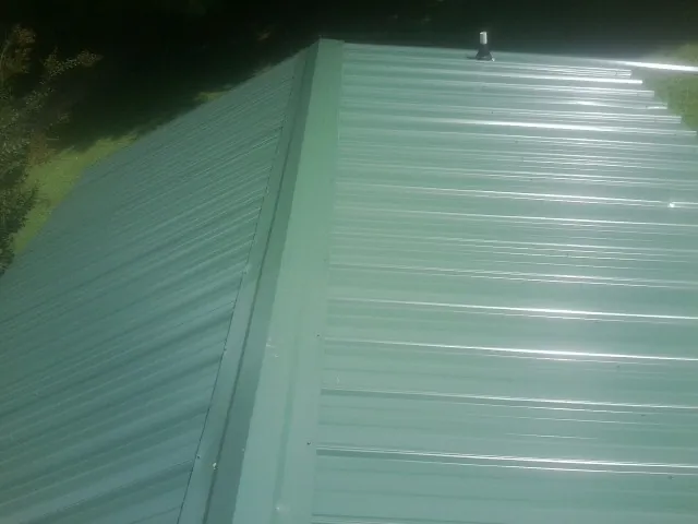 New green metal panels meeting at the ridge of a roof — Flat Roof Repair work by our crew in Lincolnwood