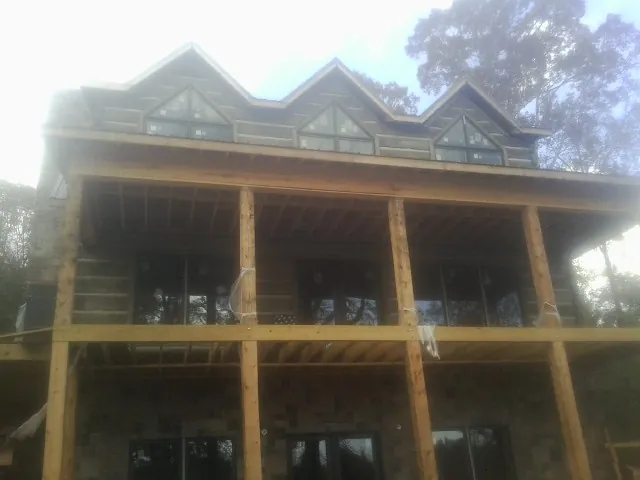 Dormers and porch framing on a large log home under construction — Roof Coating work by our crew in Lincolnwood