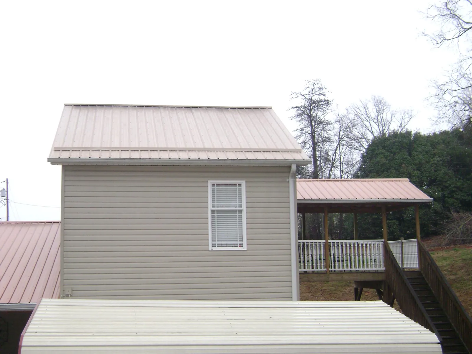 Tan metal roofs on a two story addition and attached porch, from a Roof Replacement job in Lincolnwood