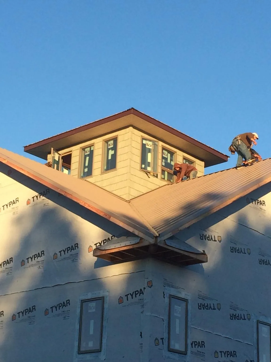 Roofers working around a rooftop cupola on a new metal roof at sunset — Roof Waterproofing in Lincolnwood by Roofing Brothers